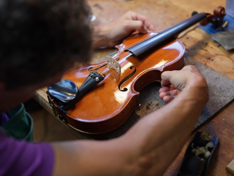 Violin maker building a violin in his workshop. Horizontal shot.